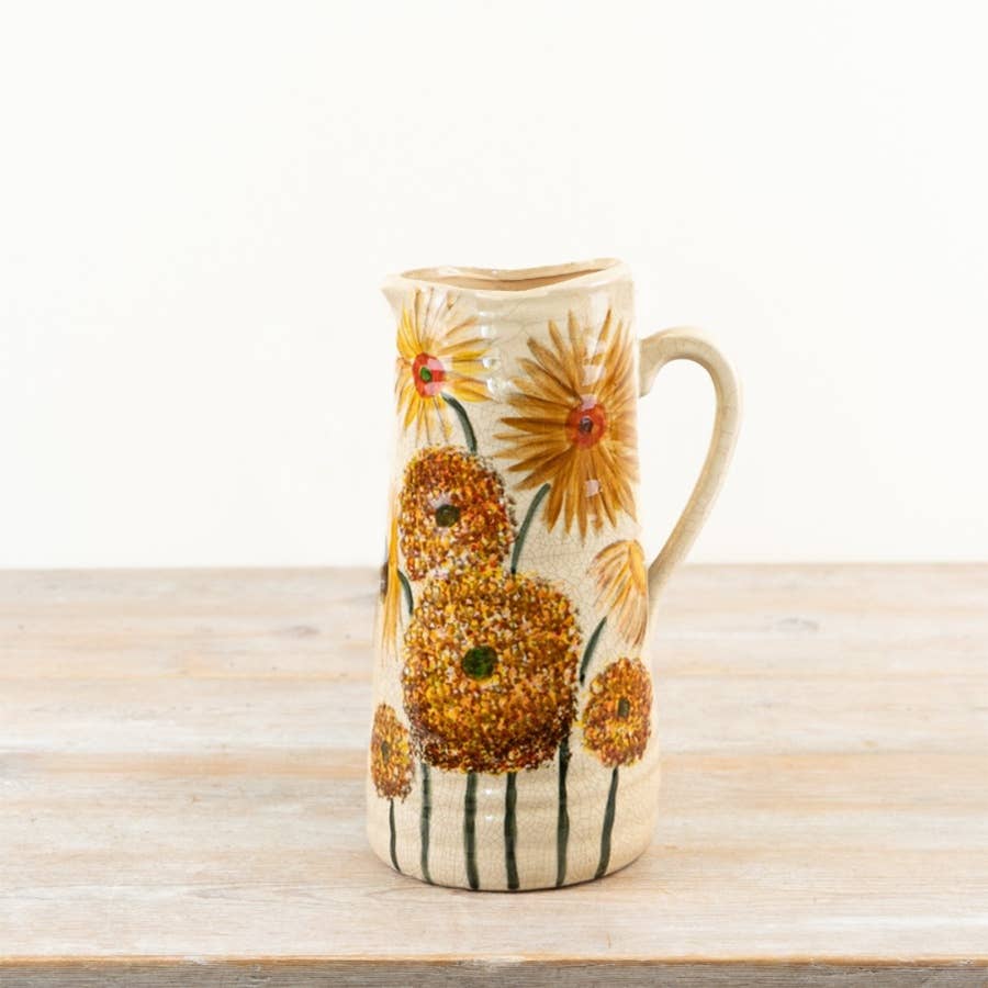 Ceramic pitcher with sunflower design on a wooden surface