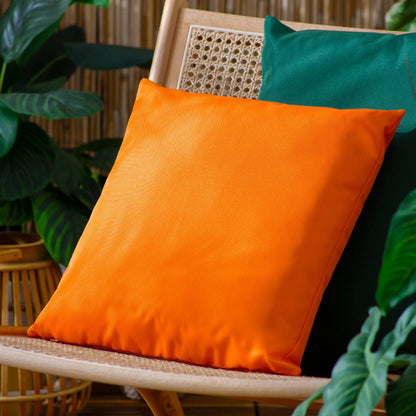 Vibrant orange outdoor cushion made from water-resistant polyester on a garden chair."