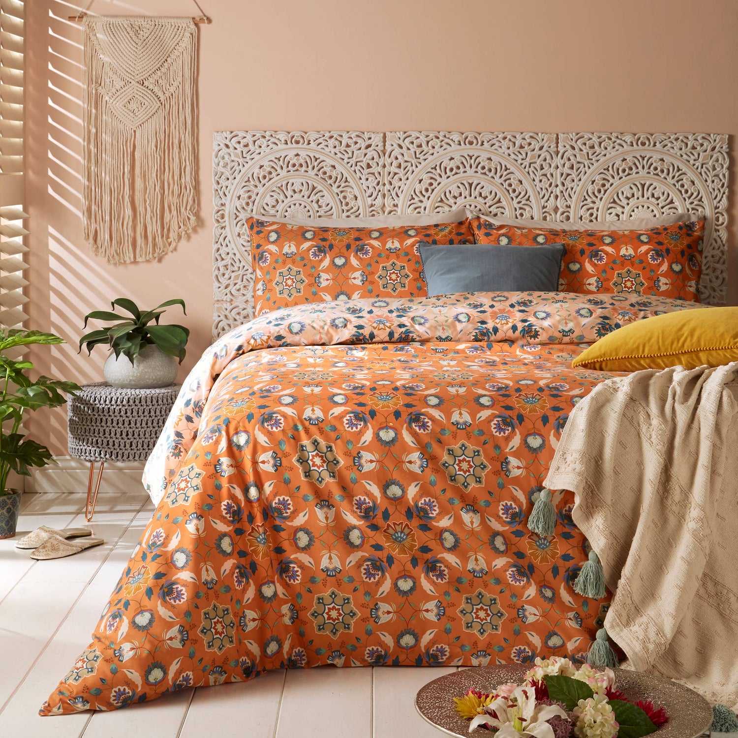 Bed with orange folk art floral bedding in a bedroom setting