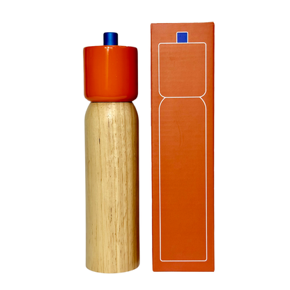 Wooden pepper grinder with an orange top and packaging on a white background