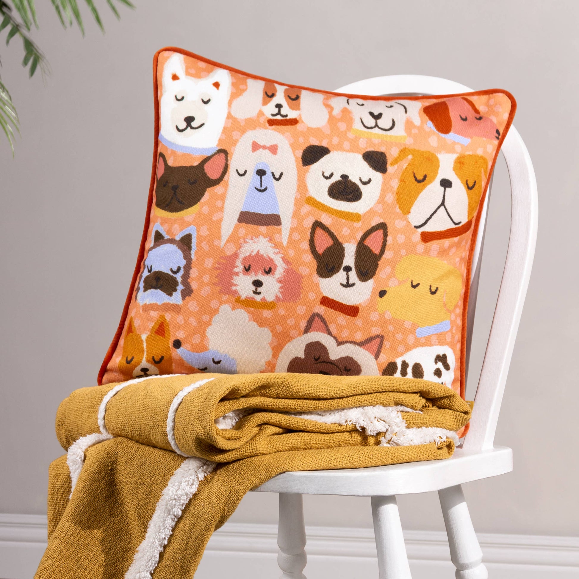 Decorative pillow with dog pattern on a white chair with a yellow blanket.