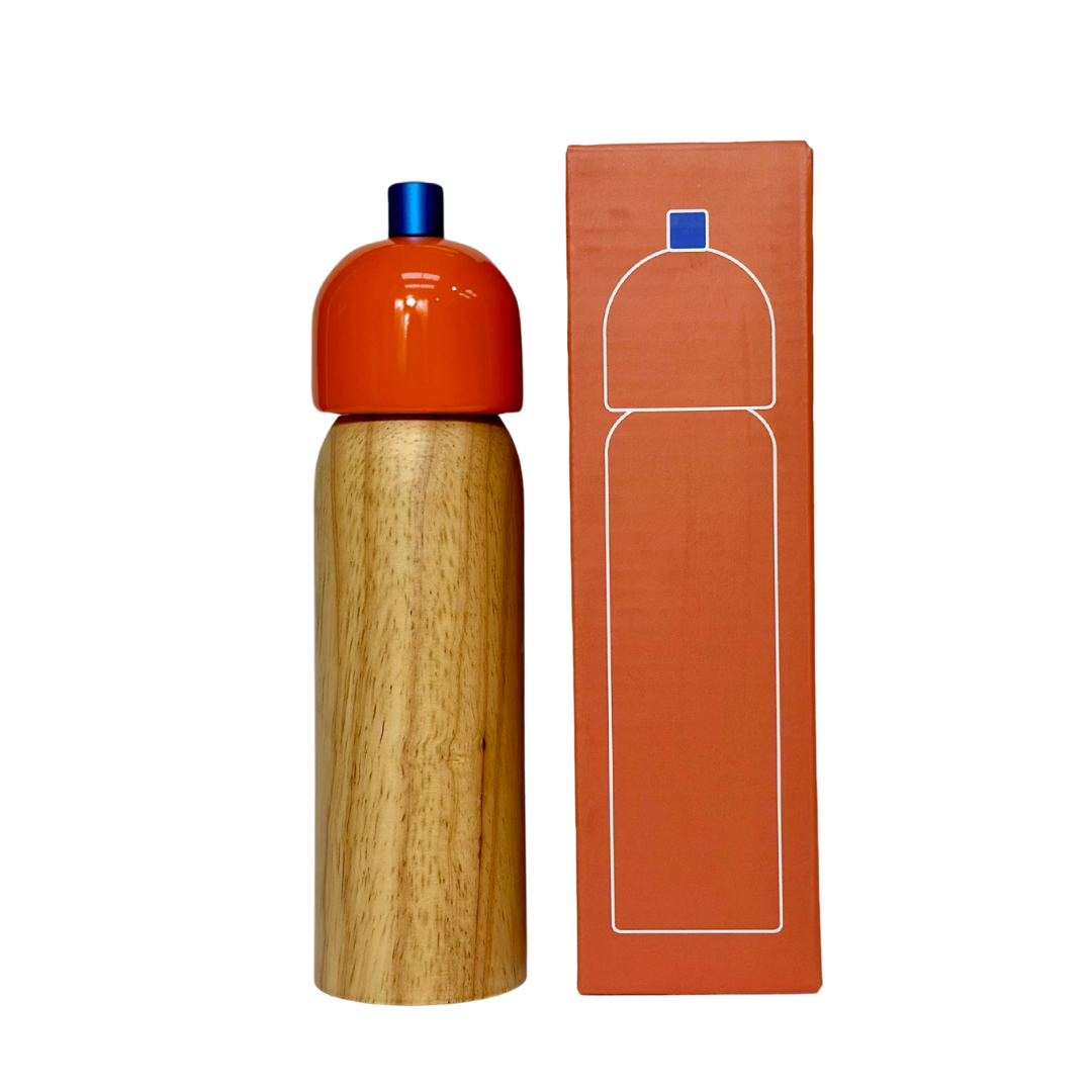 Wooden grinder with orange cap and blue top, next to its packaging on a white background