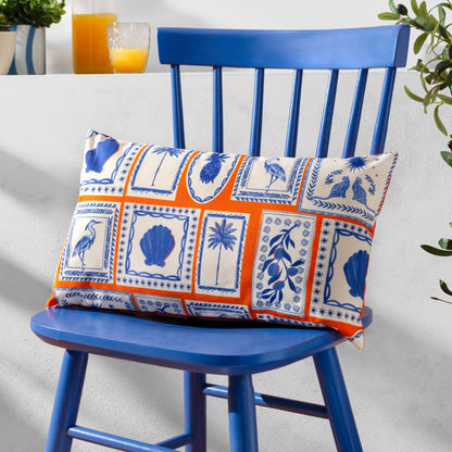 Reversible Greek-inspired outdoor cushion with blue island symbols and an orange reverse, styled on a blue chair 