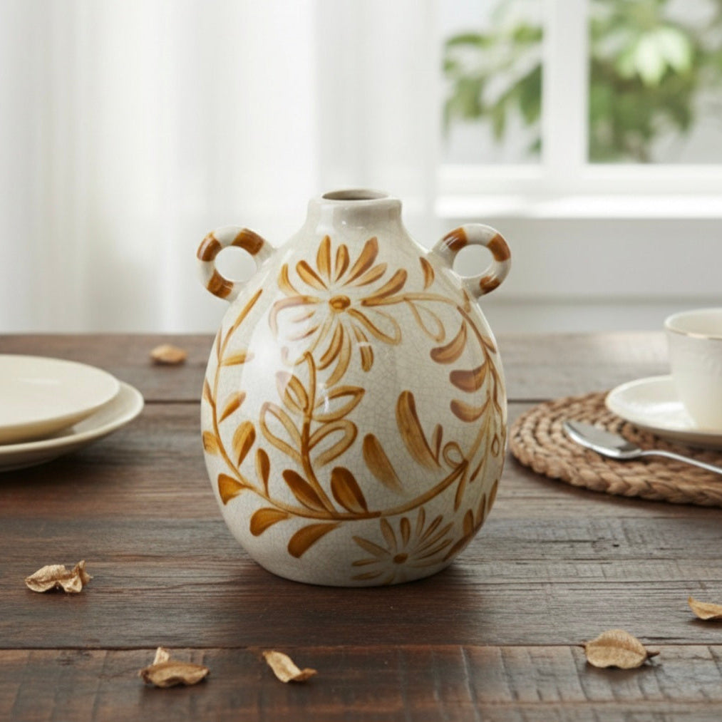 Double-handled ceramic vase with a hand-painted ochre floral design and white crackle glaze on a wooden table