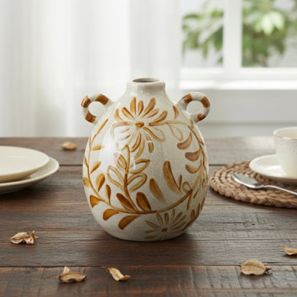 Double-handled ceramic vase with a hand-painted ochre floral design and white crackle glaze on a wooden table