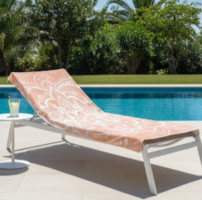 Orange ombre mandala beach towel on a white sunlounger next to a swimming pool