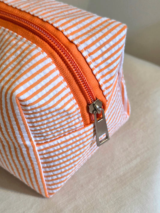 Striped fabric pouch with orange zipper on a light background