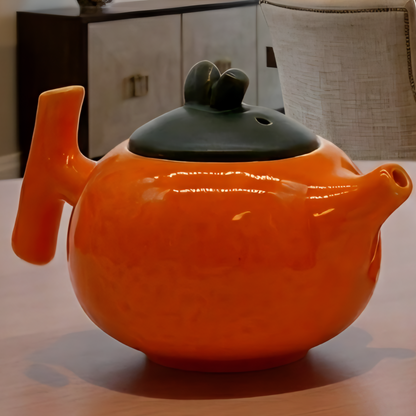 Orange ceramic teapot and bowls on a table with a living room background