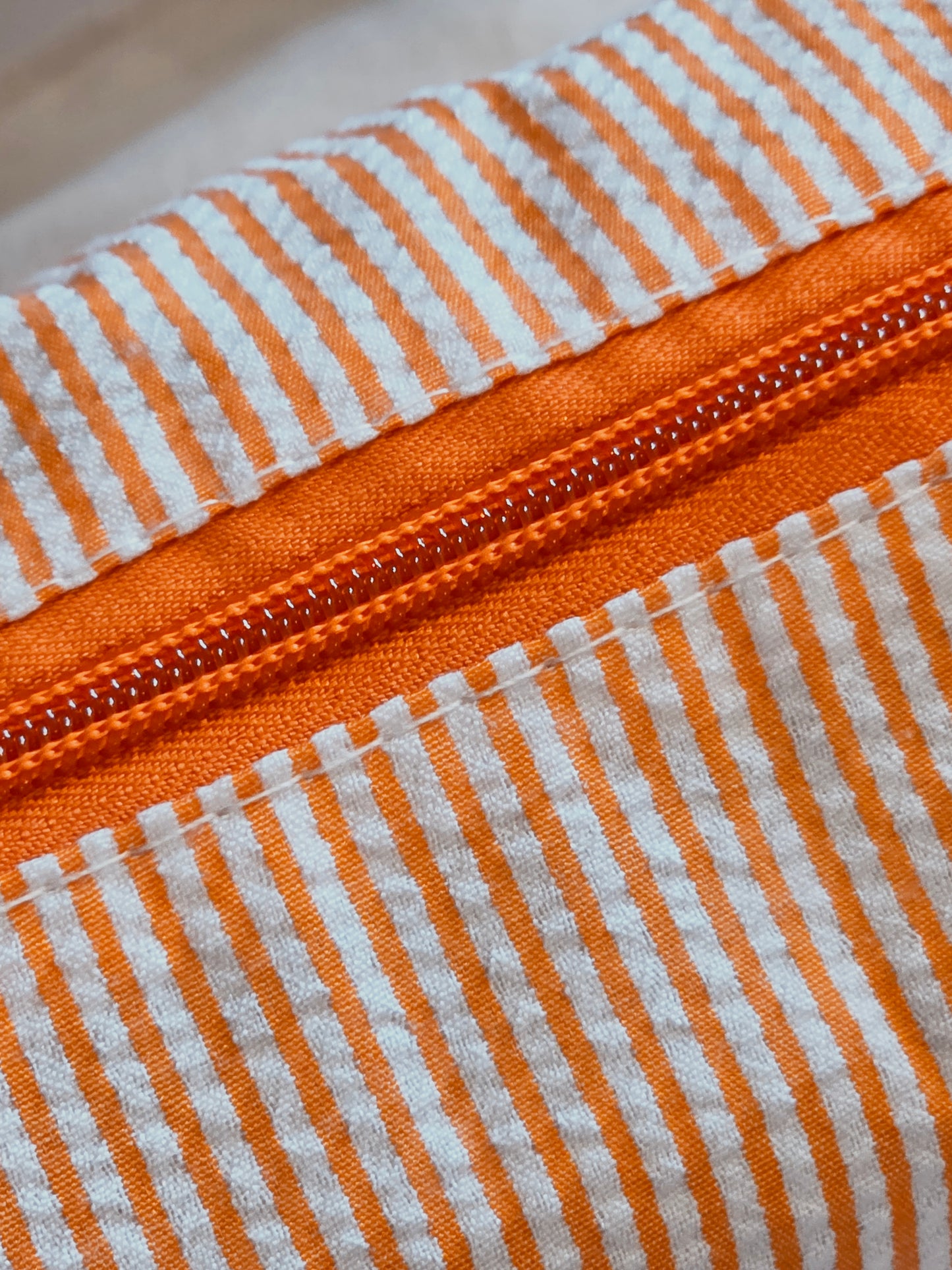 Close-up of an orange and white striped fabric with a zipper.