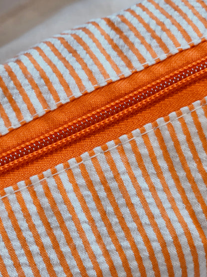 Close-up of an orange and white striped fabric with a zipper.